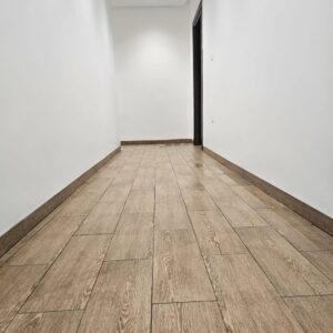 بلاط أرضيات بمظهر خشبي في ممر بعد التنظيف يظهر بشكل نظيف ولامع مع تفاصيل واضحة